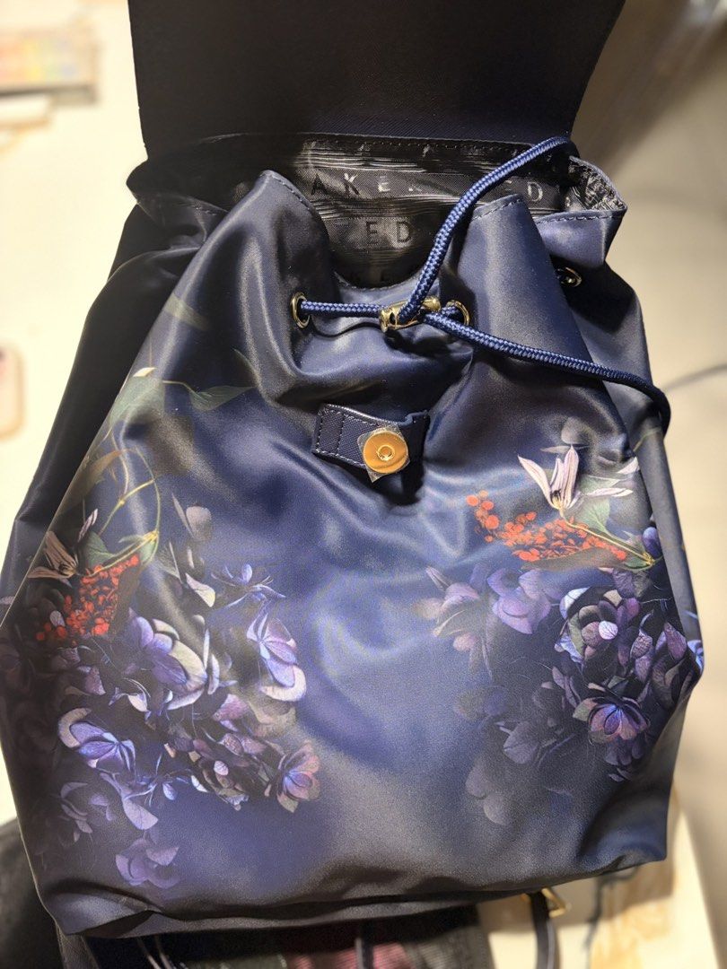 Ted Baker London Floral Nylon Backpack (Category: Backpacks) located in Pasig City. Submitted by bituin18 (Listing ID 1470084071, Image 3). Description: - Brand new with original tags attached - Authentic Ted Baker blue nylon backpack with dark floral print - Elegant gold-tone hardware accents - Secure flap top with magnetic snap and drawstring cinch closure - Signature logo jacquard interior lining - Adjustable shoulder straps and convenient top