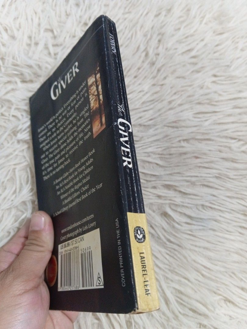 The Giver by Lois Lowry Laurel-Leaf Paperback (Category: Storybooks) located in Cavite. Submitted by nathstelein_finds (Listing ID 1470118682, Image 3). Description: - Title & Author: The Giver by Lois Lowry - Edition & Format: Laurel-Leaf paperback edition with black cover - Genre: Classic dystopian novel - Condition: Pages have natural yellowing and age spots around the edges; spine is intact with standard shelf wear - Details: ISBN barcode vis