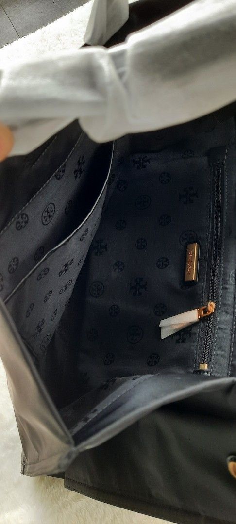 Tory Burch Black Nylon Tote Bag (Category: Tote Bags) located in Manila. Submitted by gracjam_27 (Listing ID 1470030199, Image 3). Description: - Brand new with store tag and matching dust bag - Authentic Tory Burch black nylon tote with chic leather trim corners and straps - Large tonal logo patch on the front with sophisticated gold-tone hardware - Handles still wrapped in original protective paper - Spacious interior featuring a secure zip poc
