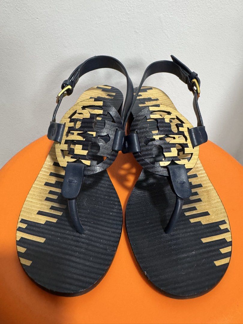 Tory Burch Block Heel Sandals (Category: Flats & Sandals) located in Valenzuela. Submitted by sofiasticated.decluttering (Listing ID 1470000331, Image 2). Description: - Brand: Tory Burch - Size: 7M - Color: Navy blue and Gold - Material/Origin: Made in Brazil - Design: Iconic front logo cutout with slingback and adjustable gold-tone buckle - Heel: Solid block heel for stability and all-day comfort - Details: Distinctive patterned footbed - Condi