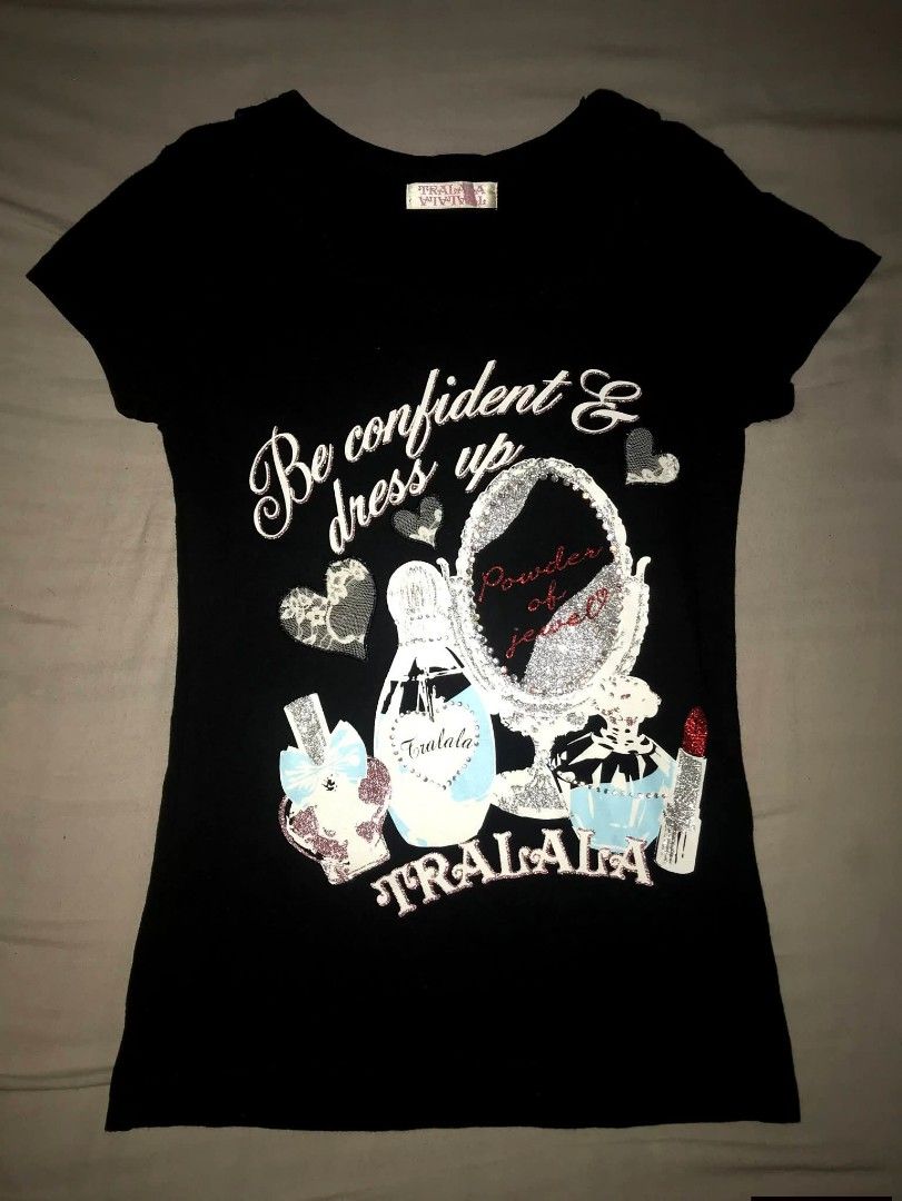 Tralala Black Graphic T-Shirt (Category: Shirts) located in Iloilo. Submitted by junpopakoto (Listing ID 1470127153, Image 1). Description: - Brand: Tralala (authentic Japanese brand label at inner neck) - Color: Classic black with short sleeves and a scoop neckline - Front Design: Chic makeup bottles, mirror, and 'Be confident and dress up' text - Back Design: Small gem-encrusted compact makeup graphic with 'Lovely style' text - Condition: Excel