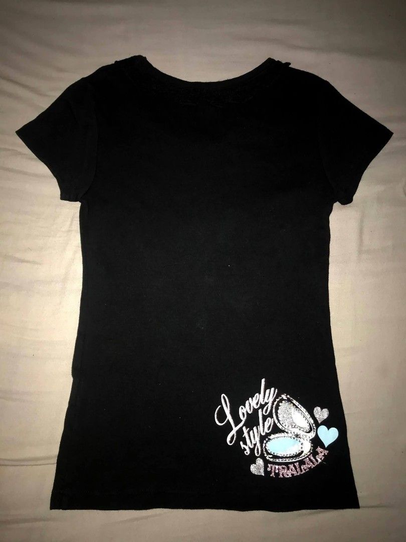 Tralala Black Graphic T-Shirt (Category: Shirts) located in Iloilo. Submitted by junpopakoto (Listing ID 1470127153, Image 2). Description: - Brand: Tralala (authentic Japanese brand label at inner neck) - Color: Classic black with short sleeves and a scoop neckline - Front Design: Chic makeup bottles, mirror, and 'Be confident and dress up' text - Back Design: Small gem-encrusted compact makeup graphic with 'Lovely style' text - Condition: Excel