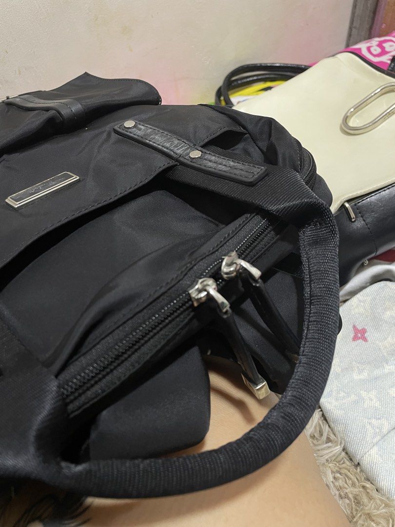 TUMI Black Nylon Backpack with Multiple Pockets (Category: Backpacks) located in Santiago. Submitted by UkayLuxxSelector (Listing ID 1470091244, Image 3). Description: Black Tumi backpack made of durable nylon material. Structured top handles plus adjustable shoulder straps on the back. Front exterior features a zipped section and a large flap pocket with dual strap closures. Main compartment lined in neutral beige fabric, containing internal lap