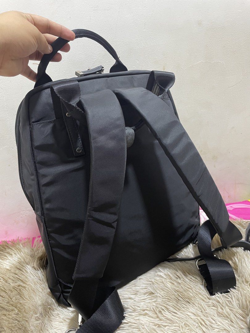 TUMI Black Nylon Backpack with Multiple Pockets (Category: Backpacks) located in Santiago. Submitted by UkayLuxxSelector (Listing ID 1470091244, Image 2). Description: Black Tumi backpack made of durable nylon material. Structured top handles plus adjustable shoulder straps on the back. Front exterior features a zipped section and a large flap pocket with dual strap closures. Main compartment lined in neutral beige fabric, containing internal lap