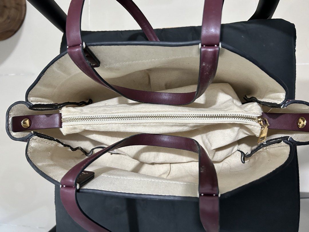 Two-Tone Canvas and Maroon Leather Tote Bag (Category: Tote Bags) located in Quezon City. Submitted by saltynsweetluvr (Listing ID 1470036950, Image 2). Description: - Color & Material: Beige canvas body with deep maroon leather trim - Hardware: Gold-tone accents with a secure top zip closure - Interior: Clean fabric-lined with generous space for daily essentials - Condition: Excellent structure, very clean inside and out.