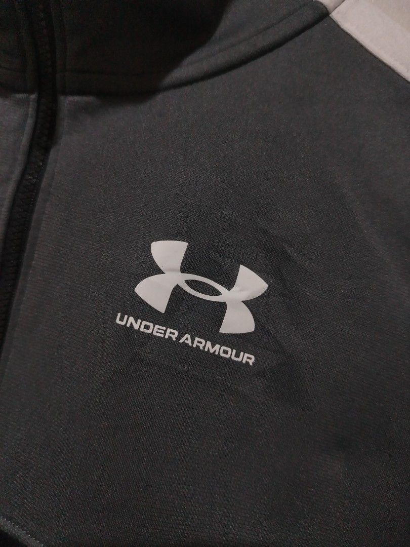 Under Armour Full-Zip Track Jacket (Category: Coats, Jackets and Outerwear) located in Rizal. Submitted by gmpastoffi75031 (Listing ID 1470012021, Image 2). Description: - Brand: Under Armour - dimes 18.5x25 - Color: Grey and black with white contrast sleeve stripes - Size: Youth Extra Large (Loose fit) - Design: Full zip front closure with a high collar - Material: 100% polyester body, 91% polyester rib - Care: Wash instructions printed on insid