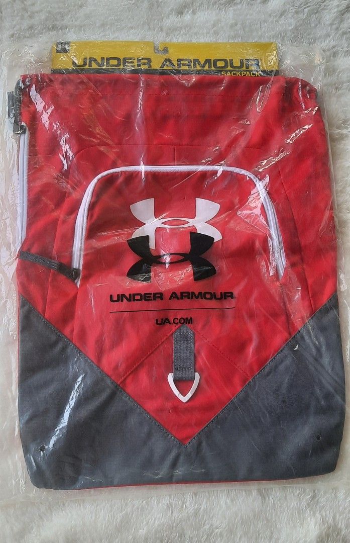 Under Armour Sackpack Red Grey Gym Bag (Category: Backpacks) located in Manila. Submitted by gracjam_27 (Listing ID 1470028435, Image 1). Description: - Brand: Under Armour - Color: Red and dark grey with white branding - Condition: Brand new, still sealed in original plastic packaging with hanger tag - Features: Lightweight drawstring design, front zipper pocket, and bottom triangle panel detail.