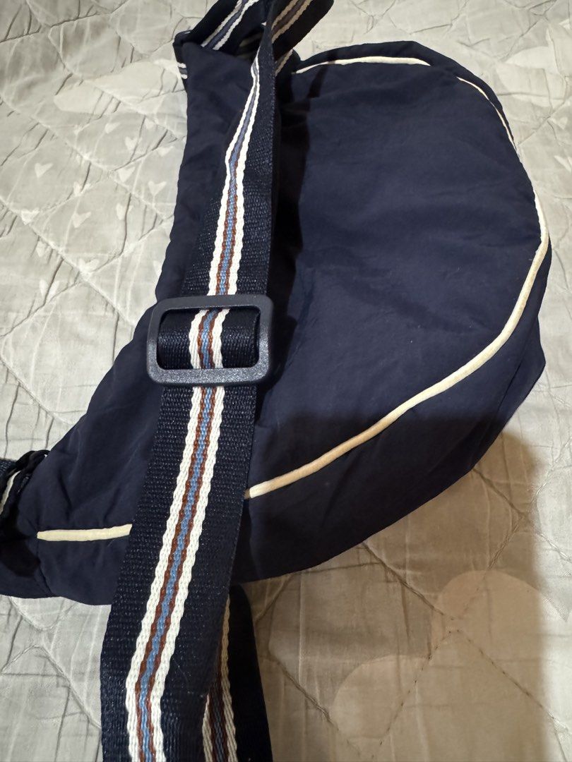 UNIQLO dumpling slingbag (Category: Shoulder Bags) located in Danao, Cebu. Submitted by jojie.1983 (Listing ID 1470015754, Image 3). Description: - Brand: UNIQLO - Style: Crescent-shaped crossbody bag - Color: Dark blue with blue and brown striped adjustable strap - Closure: Zippered main compartment with fabric lining - Condition: Clean interior and exterior, excellent pre-loved condition - Features: Practical size for daily essentials and verif
