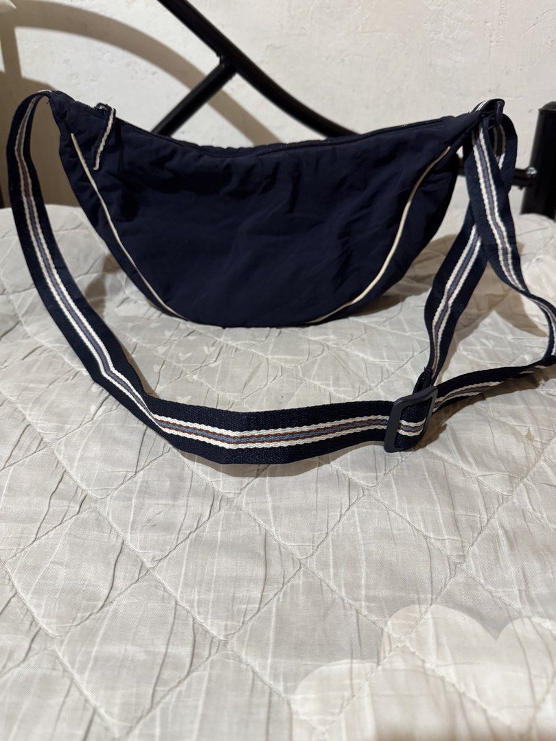 UNIQLO dumpling slingbag (Category: Shoulder Bags) located in Danao, Cebu. Submitted by jojie.1983 (Listing ID 1470015754, Image 1). Description: - Brand: UNIQLO - Style: Crescent-shaped crossbody bag - Color: Dark blue with blue and brown striped adjustable strap - Closure: Zippered main compartment with fabric lining - Condition: Clean interior and exterior, excellent pre-loved condition - Features: Practical size for daily essentials and verif