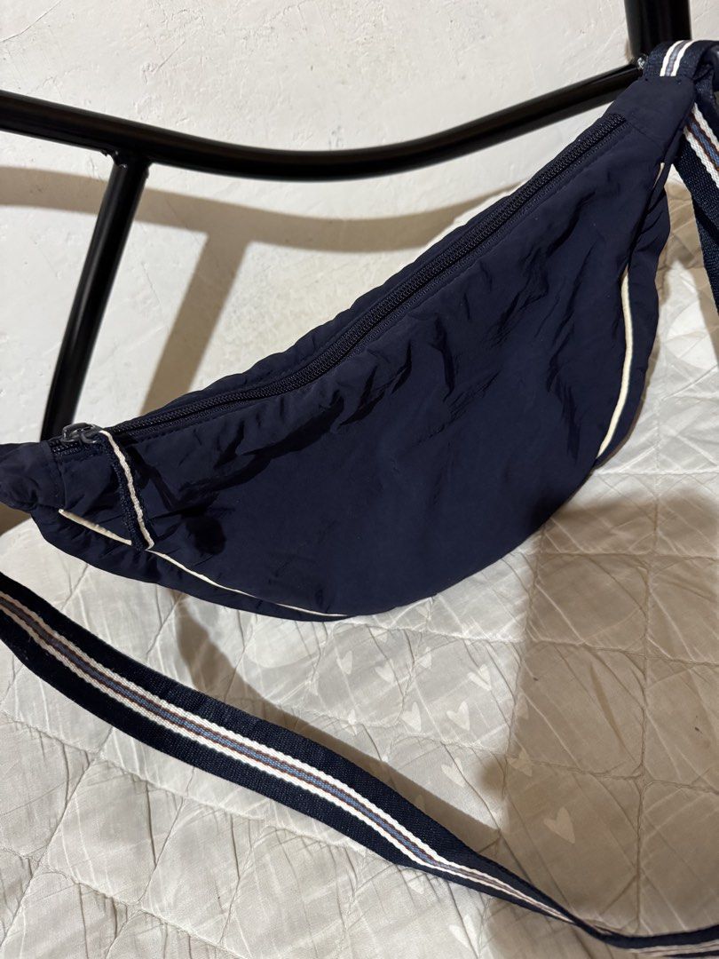 UNIQLO dumpling slingbag (Category: Shoulder Bags) located in Danao, Cebu. Submitted by jojie.1983 (Listing ID 1470015754, Image 2). Description: - Brand: UNIQLO - Style: Crescent-shaped crossbody bag - Color: Dark blue with blue and brown striped adjustable strap - Closure: Zippered main compartment with fabric lining - Condition: Clean interior and exterior, excellent pre-loved condition - Features: Practical size for daily essentials and verif