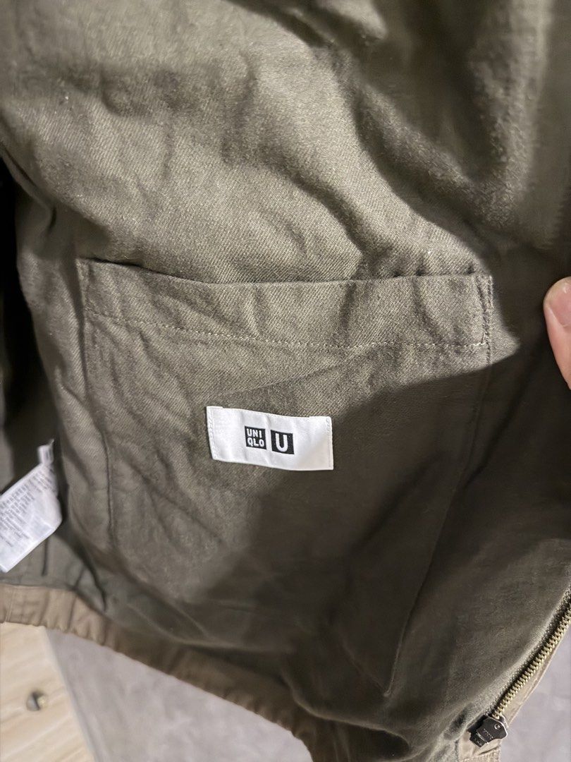 Uniqlo U Olive Green Utility Jacket (Category: Coats, Jackets and Outerwear) located in Santa Rosa. Submitted by jericobngo (Listing ID 1469951991, Image 3). Description: - Brand/Collection: Uniqlo U - Color: Olive green (earthy tone) - Features: Pointed collar, full zip front with snap button closure, and multiple front pockets - Fabric: Resinated fabric coating with care instructions on the inner tag - Styling: Perfect for easy layering over ho