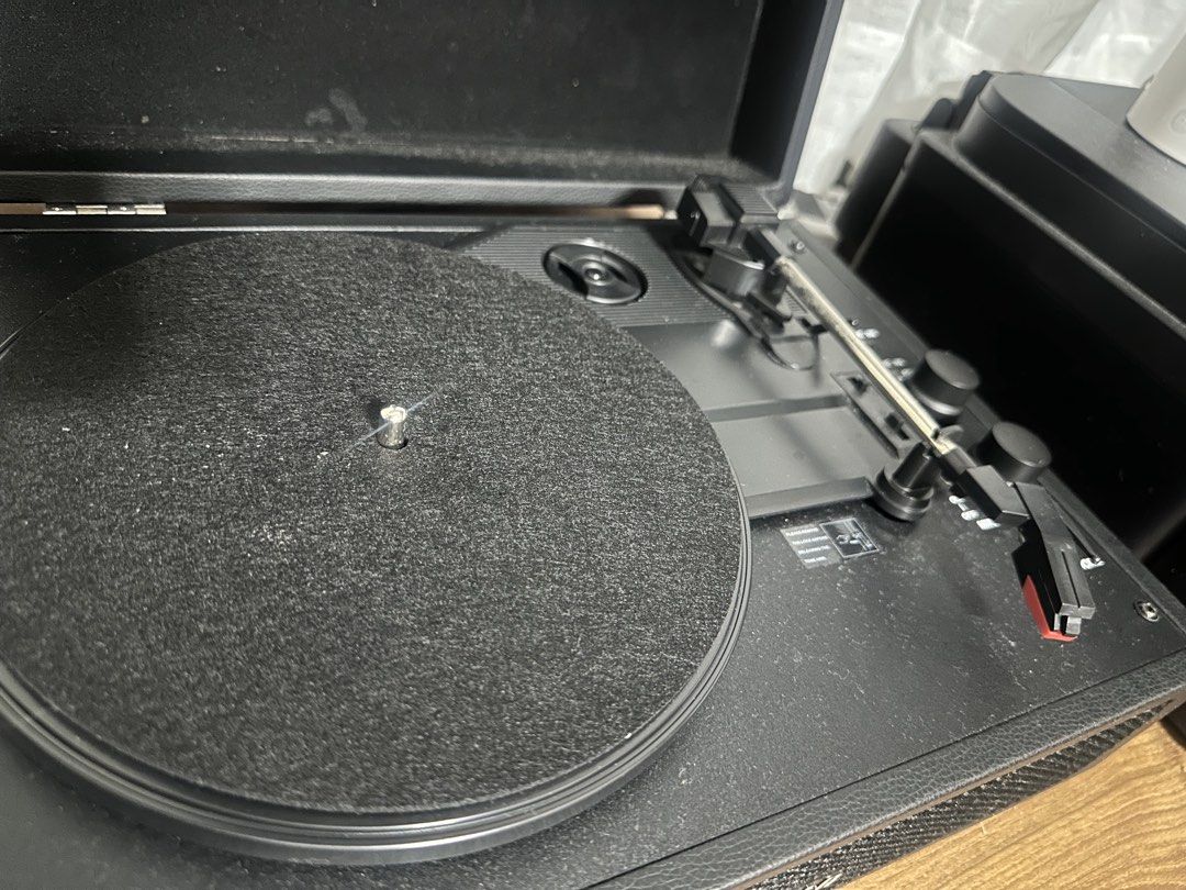 Victrola Portable Suitcase Vinyl Record Player (Category: Portable Music Players) located in Quezon City. Submitted by boshb (Listing ID 1469953978, Image 2). Description: - Model: Black Victrola suitcase-style turntable - Condition: Powers on and plays records normally (has minor surface dust) - Sound: Built-in speakers behind front mesh grille - Controls & Ports: Multiple volume/mode knobs, headphone jack, and line-in ports - Components: Standa