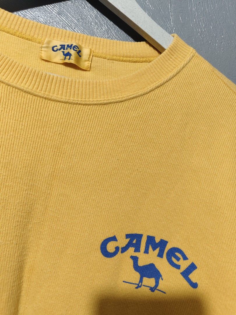 Vintage Camel Yellow Sweatshirt Blue Logo (Category: Coats, Jackets and Outerwear) located in Daet. Submitted by eezekethrift (Listing ID 1470071763, Image 3). Description: -brand: camel - Style: Vintage crew neck pullover sweatshirt - Color: Bright yellow with blue graphics on chest and back - Features: Soft fabric, ribbed cuffs and hem - Condition: Pre-loved, classic vintage piece.