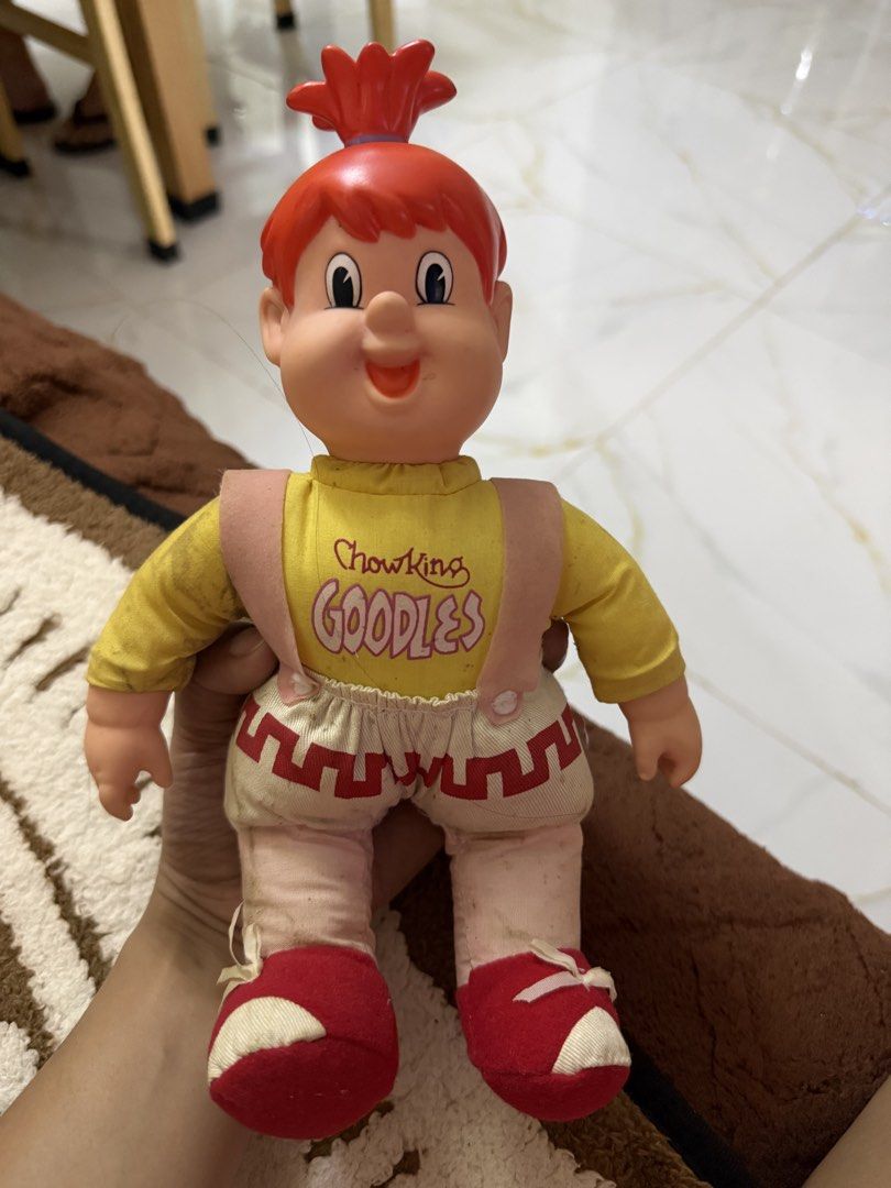 Vintage Chow King Goodles mascot plush doll (Category: Plushies & Soft Toys) located in Dasmarinas. Submitted by _adieeeee (Listing ID 1470029114, Image 3). Description: - Official Chowking Goodles promotional mascot doll - Design: Red plastic hair/head, yellow long-sleeve shirt with pink print, cream shorts with red hem, pink straps, and red shoes - Condition: Hard parts are fully intact - Note: Fabric shows minor dirt marks due to age and handl