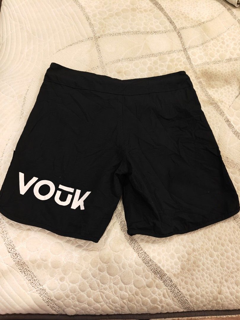 Vouuk Fight Shorts Black (Category: Shorts) located in Manila. Submitted by thriftnmeal (Listing ID 1470017265, Image 2). Description: - Brand: Vouuk - Color: Black with white logo text and geometric wolf graphic - Fit & Closure: Velcro waist closure with a drawstring channel - Mobility: Side slits for enhanced movement during training - Condition: Good overall, with a small tear on the fabric near the hem - Sizing: Tag indicates size.