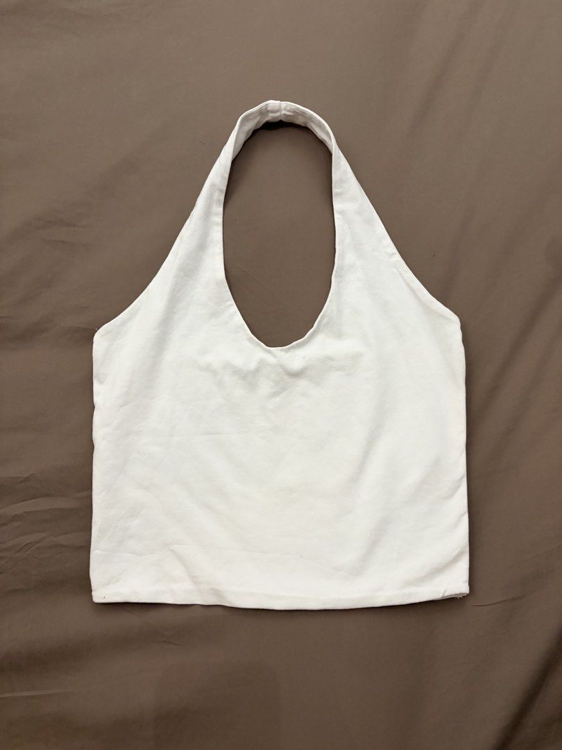 White Halter Top (Category: Sleeveless) located in Pasig City. Submitted by gdeclutterwithme (Listing ID 1470115717, Image 1). Description: - Brand: Stradivarius - Size: M (fits EUR, USA, MEX) - Color: White - Style: Classic minimalist halter top with deep scoop neckline and back, thick shoulder straps - Material: Soft cotton fabric - Versatility: Easy to style with high-waisted jeans or skirts dm for more deets!.