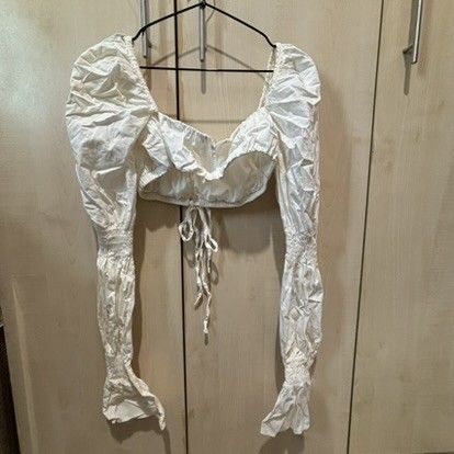 White long sleeve crop top with puff sleeves (Category: Longsleeves) located in Quezon City. Submitted by slvrbullet (Listing ID 1470139964, Image 1). Description: - Color: White - Style: Crop top with long puff sleeves and smocked cuffs - Neckline: Square neck with a cute front tie string detail - Fit: Short cropped length, lightweight fabric - Styling: Perfect to pair with high-waisted jeans or skirts - Condition: Wrinkled from storage, needs i