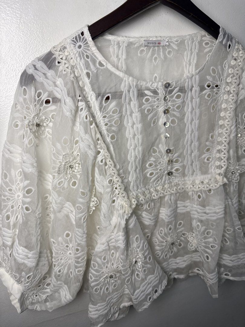 JESSICA White Lace Embroidered Blouse (Category: Blouses) located in Quezon City. Submitted by dropdeadprices (Listing ID 1470078765, Image 3). Description: - Brand/Label: Jessica Red - Size: P - Color: White (sheer) - Details: Cutwork embroidery, floral patterns, textured panels - Neckline & Closure: Round neck with mother-of-pearl style front buttons - Sleeves: Relaxed three-quarter length - Condition: Clean and well-kept.