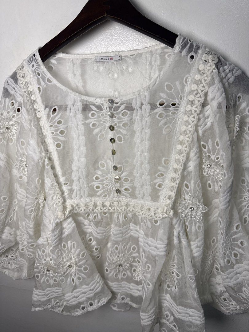 JESSICA White Lace Embroidered Blouse (Category: Blouses) located in Quezon City. Submitted by dropdeadprices (Listing ID 1470078765, Image 2). Description: - Brand/Label: Jessica Red - Size: P - Color: White (sheer) - Details: Cutwork embroidery, floral patterns, textured panels - Neckline & Closure: Round neck with mother-of-pearl style front buttons - Sleeves: Relaxed three-quarter length - Condition: Clean and well-kept.