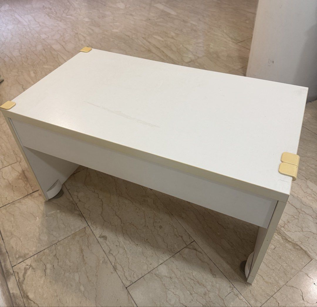 White Table (Category: Tables & Sets) located in Singapore. Submitted by kohkacola (Listing ID 1470139677, Image 3). Description: Length - 90cm Breath -50cm Height -50cm - Colour/Shape: White, simple rectangular coffee table - Build: Sturdy solid panel legs, standard living room height - Safety: Yellow corner guards installed on all four corners - Condition: Minor surface wear on top - Maintenance: Easy to wipe clean and fits most room layouts.