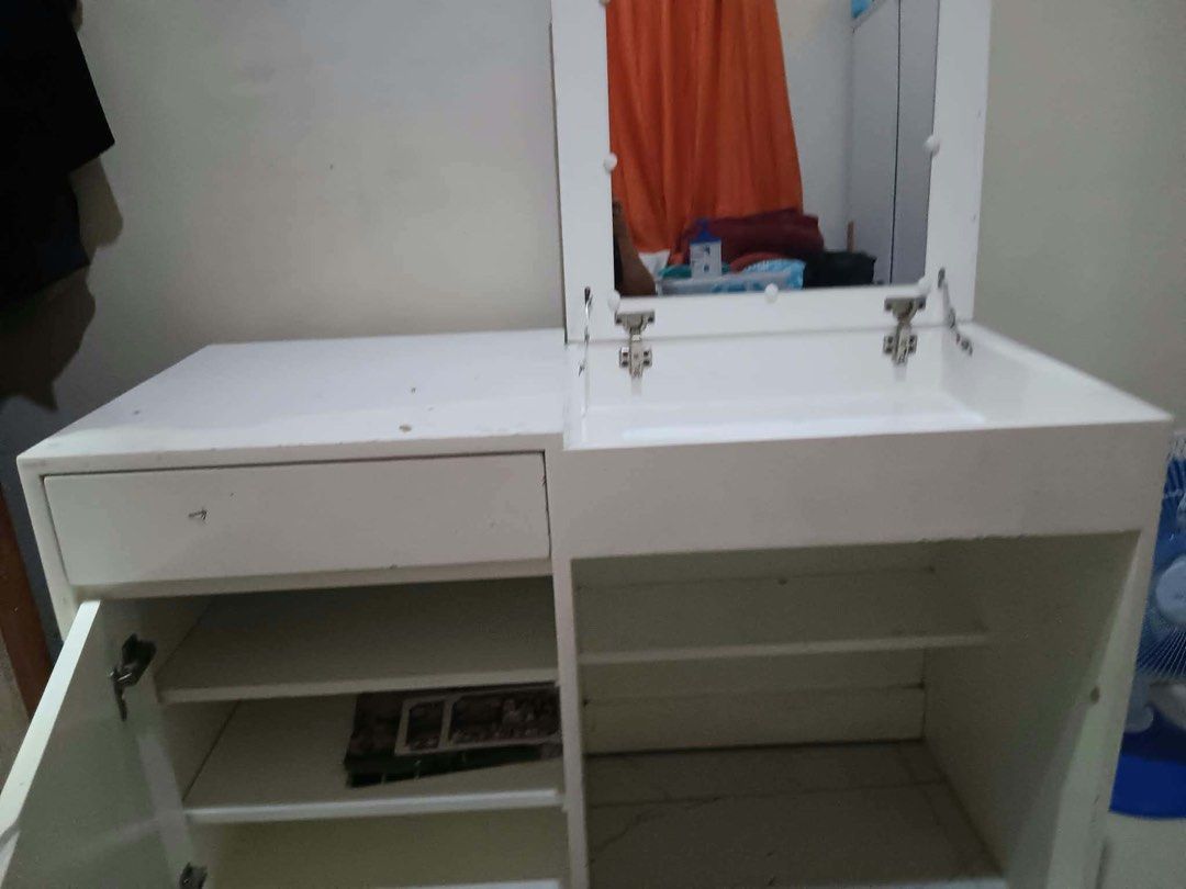 White Vanity Table with Flip-up Mirror and Storage Shelves (Category: Tables & Sets) located in Manila. Submitted by choychoy06 (Listing ID 1469992097, Image 2). Description: - Customiezd White vanity table featuring a convenient flip-mirror - Storage includes a top drawer, a lower cabinet with internal shelves, and open under-desk shelving - Please note: Shows visible scuff marks, paint chips, and surface wear across the finish - Perfect DIY mak