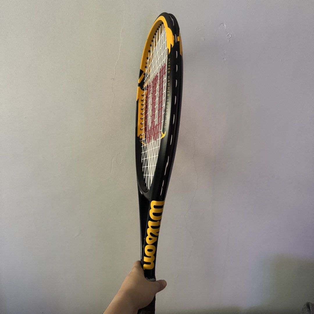Wilson Hyper Hammer Legacy Mid Tennis Racket (Category: Racket and Ball Sports) located in Dinalupihan. Submitted by alexenaaajame (Listing ID 1470000198, Image 2). Description: - Model: Wilson Hyper Hammer Legacy Mid tennis racket - Design: Classic black and yellow frame - Strings: Strung with white strings featuring the red Wilson logo - Grip: Standard handle wrapped in black tape RFS: Switch to Pickleball Bought From Chris Sports.
