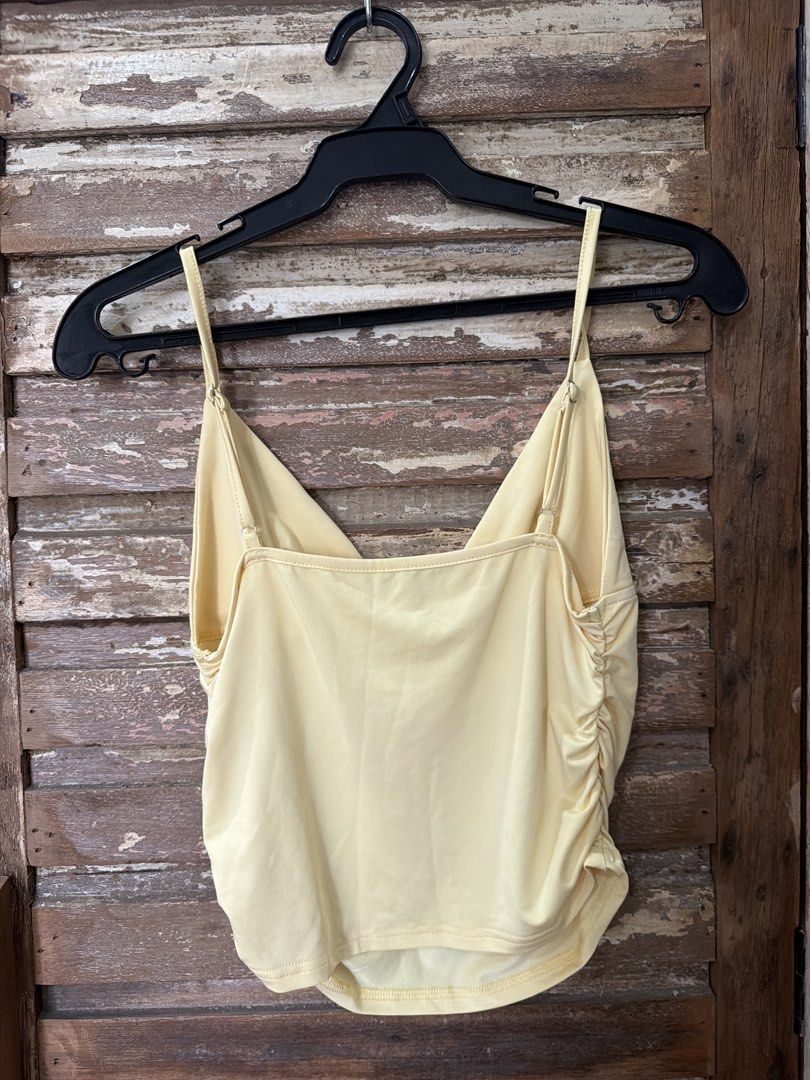 Yellow Cami Top with Ruched Sides V-Neck (Category: Sleeveless) located in Manila. Submitted by cb_____ (Listing ID 1469968735, Image 2). Description: - Color: Pastel yellow - Fit: Slightly cropped at the waist with a curved hem - Neckline: V-neck front with a straight back - Straps: Thin spaghetti straps with metal adjusters - Details: Flattering ruching gathered along both side seams - Material: Lightweight and comfortable - Condition: Clean pi