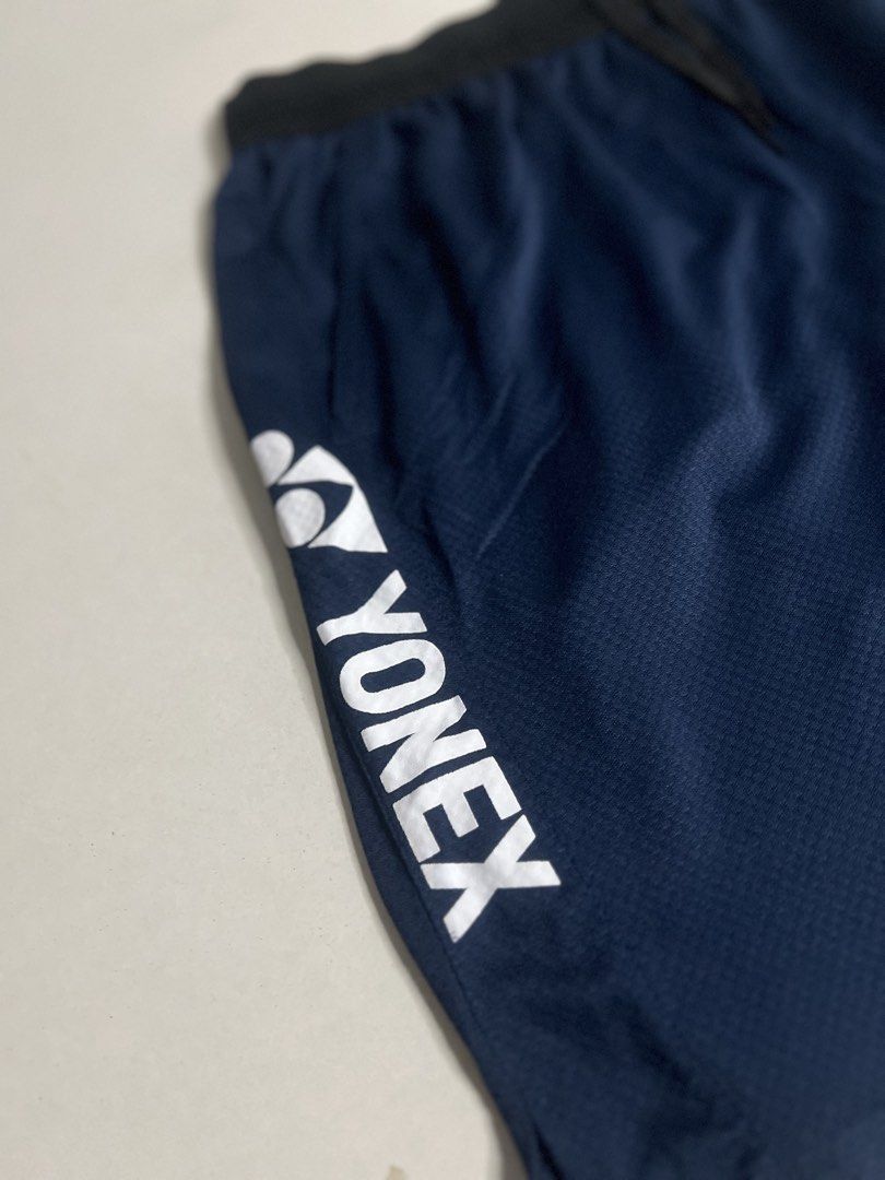 Yonex Navy Blue Athletic Shorts with Drawstring (Category: Shorts) located in Tacloban City. Submitted by thrftg (Listing ID 1470086386, Image 3). Description: - Brand: Yonex - Color: Dark Navy Blue - Material: Lightweight, breathable mesh-style fabric - Features: Elastic waistband with adjustable black drawstring - Branding: Vertical white Yonex logo on the left leg and smaller logo on the right hem - Ideal for: Badminton, tennis, and other spor