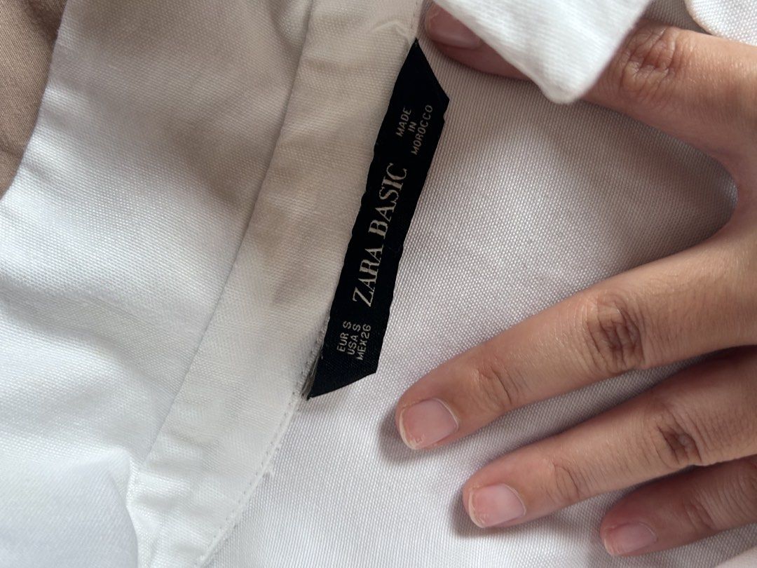 Zara Basic White Button-Down Shirt with Black Stripes Size S (Category: Shirts) located in Cebu City. Submitted by shopmikascloset (Listing ID 1469956263, Image 3). Description: - Brand: Zara Basic - Size: S (Made in Morocco) - Color: White with contrast black stripes on shoulders and sleeves - Details: Metal ring on right sleeve and single left chest pocket - Style: Standard collar, button cuffs, clean and versatile.