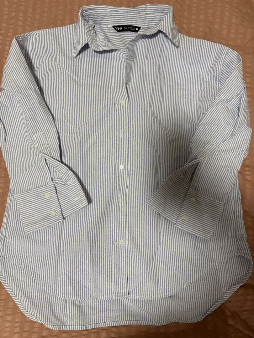 Zara Blue Striped Button-Up Shirt XS (Category: Longsleeves) located in Quezon City. Submitted by bluefrenchorn (Listing ID 1470070124, Image 1). Description: Zara blue and white striped button-down shirt. Classic collared neckline with long sleeves and button cuffs. Rounded hem at the bottom. Tag shows size XS. Measurements laid flat: pit to pit around 19 inches, length around 24 inches. Clean fabric, no flaws noticed..