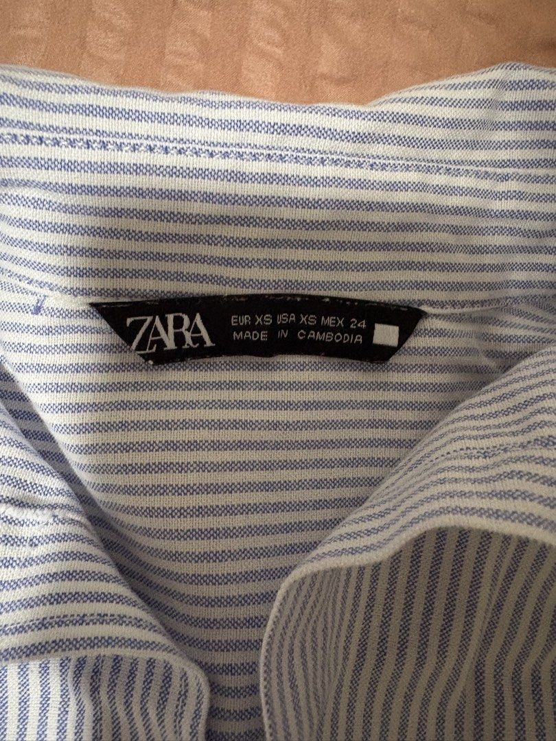 Zara Blue Striped Button-Up Shirt XS (Category: Longsleeves) located in Quezon City. Submitted by bluefrenchorn (Listing ID 1470070124, Image 2). Description: Zara blue and white striped button-down shirt. Classic collared neckline with long sleeves and button cuffs. Rounded hem at the bottom. Tag shows size XS. Measurements laid flat: pit to pit around 19 inches, length around 24 inches. Clean fabric, no flaws noticed..