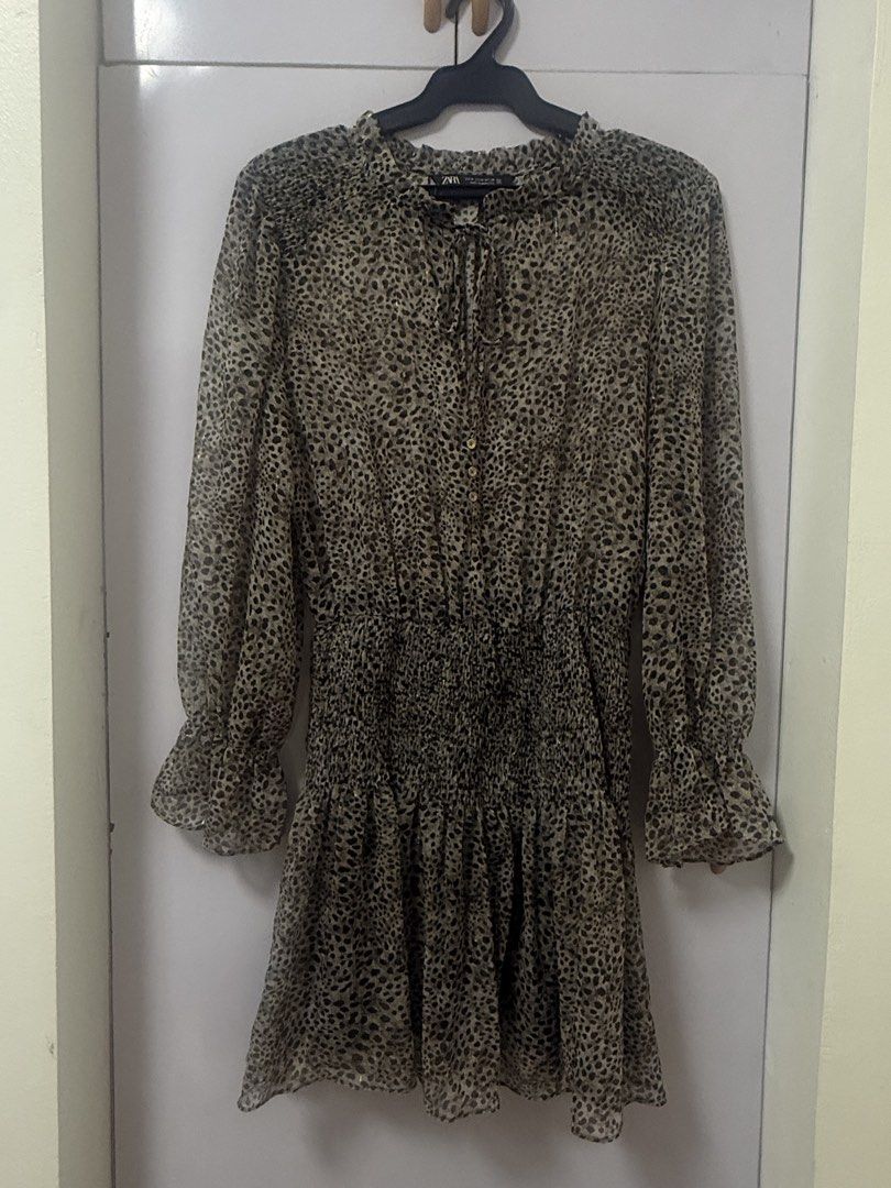 Zara Leopard Print Long Sleeve Ruffle Dress Medium (Category: Dresses) located in Quezon City. Submitted by lovedbymaxandmikoy (Listing ID 1469958203, Image 1). Description: - Brand: Zara - Size: M - Color/Pattern: Greenish beige and black animal print with subtle metallic shimmer - Material/Origin: Made in Morocco, lightweight fabric - Features: Long sleeves with ruffled cuffs, smocked elastic waist, front button placket, and neck ties - Conditi