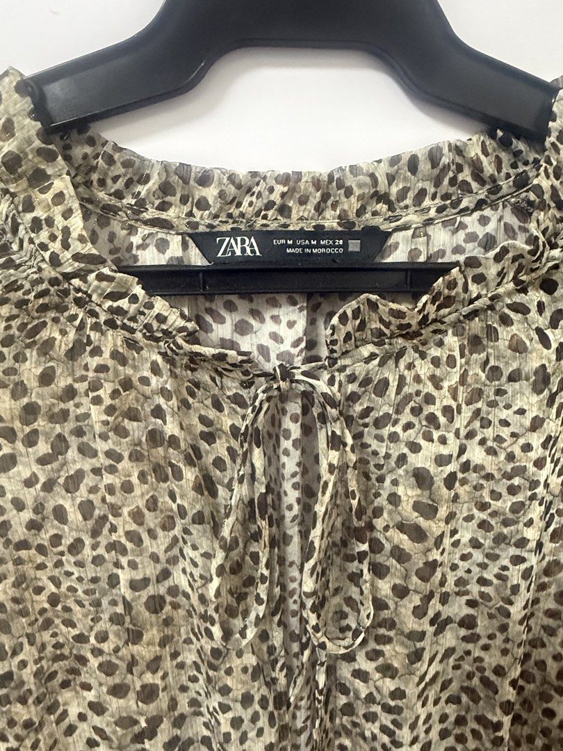 Zara Leopard Print Long Sleeve Ruffle Dress Medium (Category: Dresses) located in Quezon City. Submitted by lovedbymaxandmikoy (Listing ID 1469958203, Image 2). Description: - Brand: Zara - Size: M - Color/Pattern: Greenish beige and black animal print with subtle metallic shimmer - Material/Origin: Made in Morocco, lightweight fabric - Features: Long sleeves with ruffled cuffs, smocked elastic waist, front button placket, and neck ties - Conditi