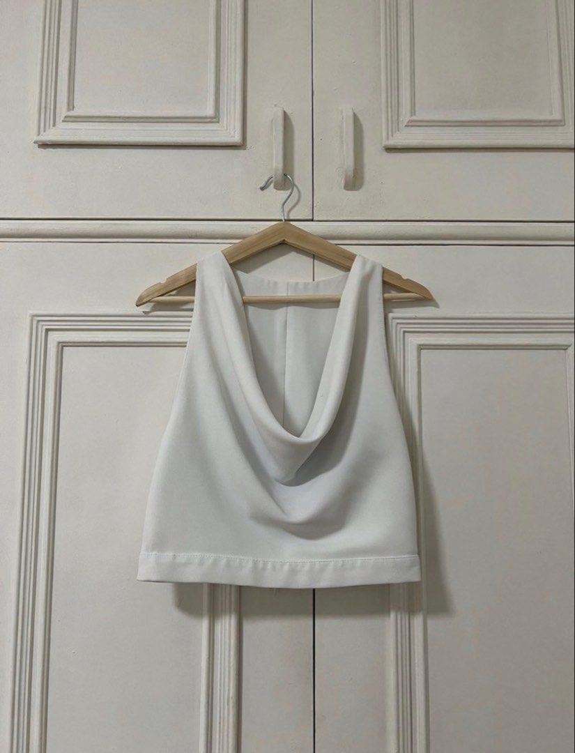 ZARA White cowl neck crop top (Category: Sleeveless) located in Dasmarinas. Submitted by aoe.ae (Listing ID 1470141270, Image 1). Description: - Color: White - Style: Sleeveless crop top with draped cowl neckline - Fit: Structured fabric that holds its shape well - Closure: Full back zipper down the middle - Versatility: Clean minimalist design that pairs easily with high-waisted skirts or trousers.
