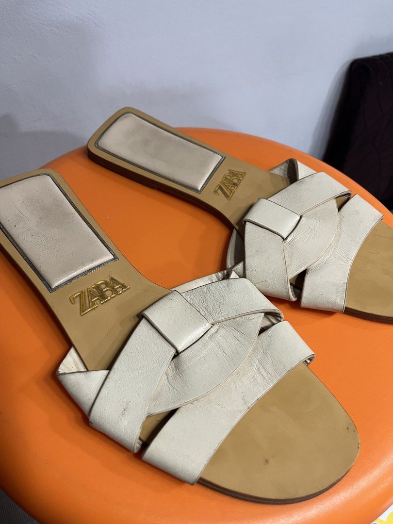 Zara White Flat Sandals (Category: Flats & Sandals) located in Valenzuela. Submitted by sofiasticated.decluttering (Listing ID 1470055738, Image 2). Description: - Brand: Zara - Style: Flat slip-on sandals - Color: White with neutral tan sole - Design: Interlocking top straps with gold logo on insole - Shape: Modern square toe with low heel - Perfect for effortless summer styling ✅PRE- OWNED and NOT suitable for picky buyers, ✅EXCELLENT CONDITION
