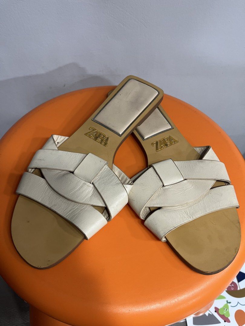 Zara White Flat Sandals (Category: Flats & Sandals) located in Valenzuela. Submitted by sofiasticated.decluttering (Listing ID 1470055738, Image 1). Description: - Brand: Zara - Style: Flat slip-on sandals - Color: White with neutral tan sole - Design: Interlocking top straps with gold logo on insole - Shape: Modern square toe with low heel - Perfect for effortless summer styling ✅PRE- OWNED and NOT suitable for picky buyers, ✅EXCELLENT CONDITION
