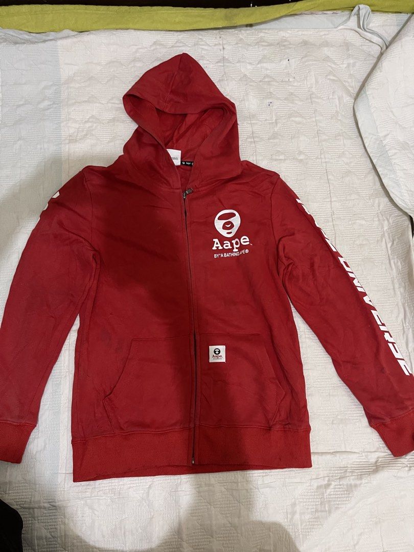 AAPE By A Bathing Ape Red Zip-Up Hoodie (Category: Babies & Kids Fashion) located in Caloocan City. Submitted by noblecat_c04f74 (Listing ID 1470153302, Image 1). Description: - Brand: AAPE by A Bathing Ape - Color: Bright red - Design: Large white ape logo on chest and 'AAPE Universe' text on sleeve - Features: Full zip-up closure, front pocket with woven brand tag, ribbed cuffs and hem - Condition: Stains (See Picture) Red color is not faded an