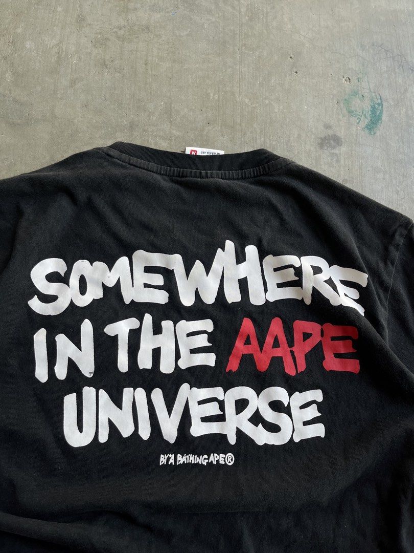 AAPE By A Bathing Ape Somewhere In The Universe Tee (Category: Tshirts & Polo Shirts ) located in Dipaculao. Submitted by _jzx.ph4lxfe (Listing ID 1470215428, Image 3). Description: - Brand: AAPE - Color: Washed black with worn-in finish - Size: Medium (M) - Design: Small rubberized logo patch on chest, large white and red back print - Details: Branded neck tape inside - Condition: Excellent pre-loved/ready to wear.