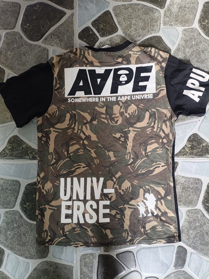 AAPE x Champion Collaboration T-Shirt (Category: Tshirts & Polo Shirts ) located in Narvacan. Submitted by picky_looter (Listing ID 1470298238, Image 2). Description: - Brand: AAPE by A Bathing Ape x Champion - Size: L (tagged at collar and sleeve) - Color: Black - Details: Front ape head and Champion chest logos, sleeve text print - Back: Distinctive camo pattern panel with large typography prints - Mode of Payment: BPI, GCash, or COD via LBC - 
