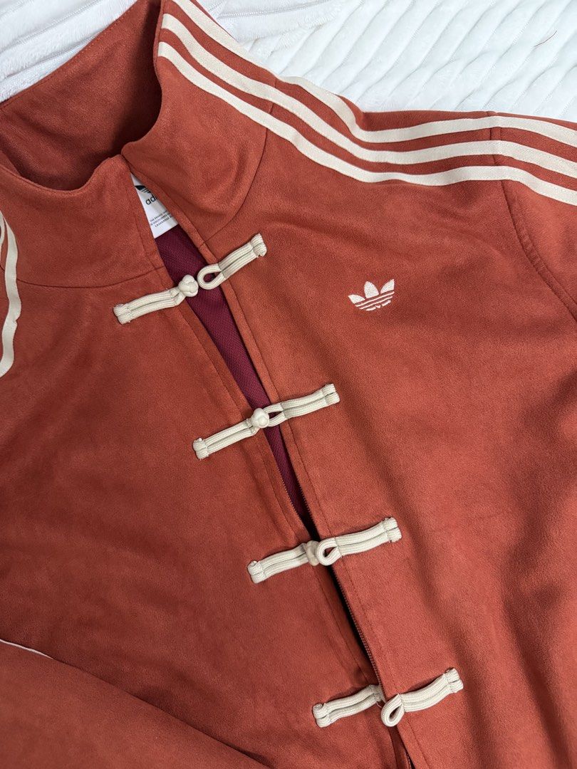 Adidas Chinese Knot Suede Track Jacket Rust Red (Category: Coats, Jackets and Outerwear) located in Rizal. Submitted by kianapreloves (Listing ID 1470237213, Image 3). Description: - Brand/Model: Adidas suede track jacket - Color: Rust red with deep red inner lining and white embroidered trefoil logo - Design: Stand-up collar with signature three stripes on sleeves - Closure: Unique combination of traditional Chinese knot buttons and front zipper