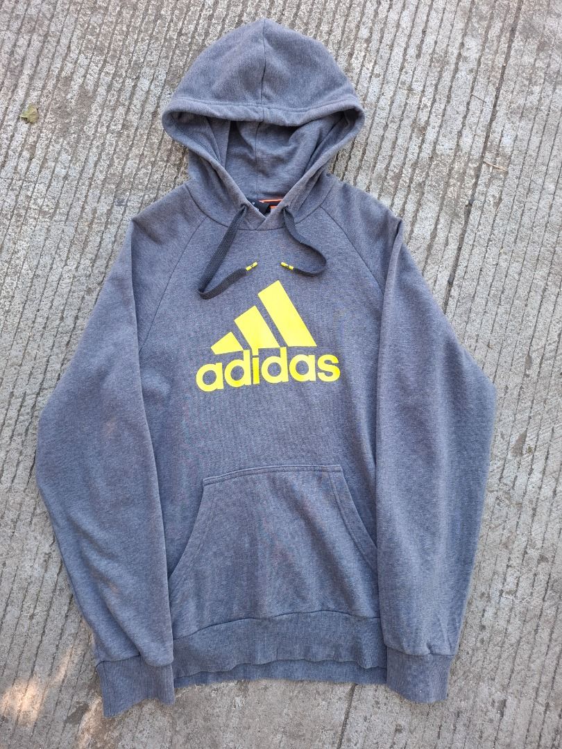 Adidas Performance Essentials Grey Yellow Hoodie Size M (Category: Hoodies) located in Caloocan City. Submitted by bobmarlou1923 (Listing ID 1470156652, Image 2). Description: - Brand: Adidas (Performance Essentials line) - Size: Medium (175/95A) - Color: Grey with striking yellow logo on the front - Material: Comfortable cotton blend with soft interior lining - Features: Adjustable drawstring hood and spacious front pouch pocket - Details: Ribbe