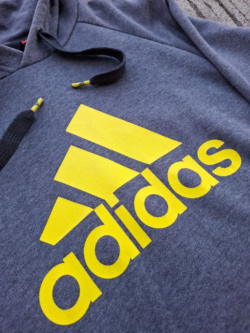 Adidas Performance Essentials Grey Yellow Hoodie Size M (Category: Hoodies) located in Caloocan City. Submitted by bobmarlou1923 (Listing ID 1470156652, Image 3). Description: - Brand: Adidas (Performance Essentials line) - Size: Medium (175/95A) - Color: Grey with striking yellow logo on the front - Material: Comfortable cotton blend with soft interior lining - Features: Adjustable drawstring hood and spacious front pouch pocket - Details: Ribbe