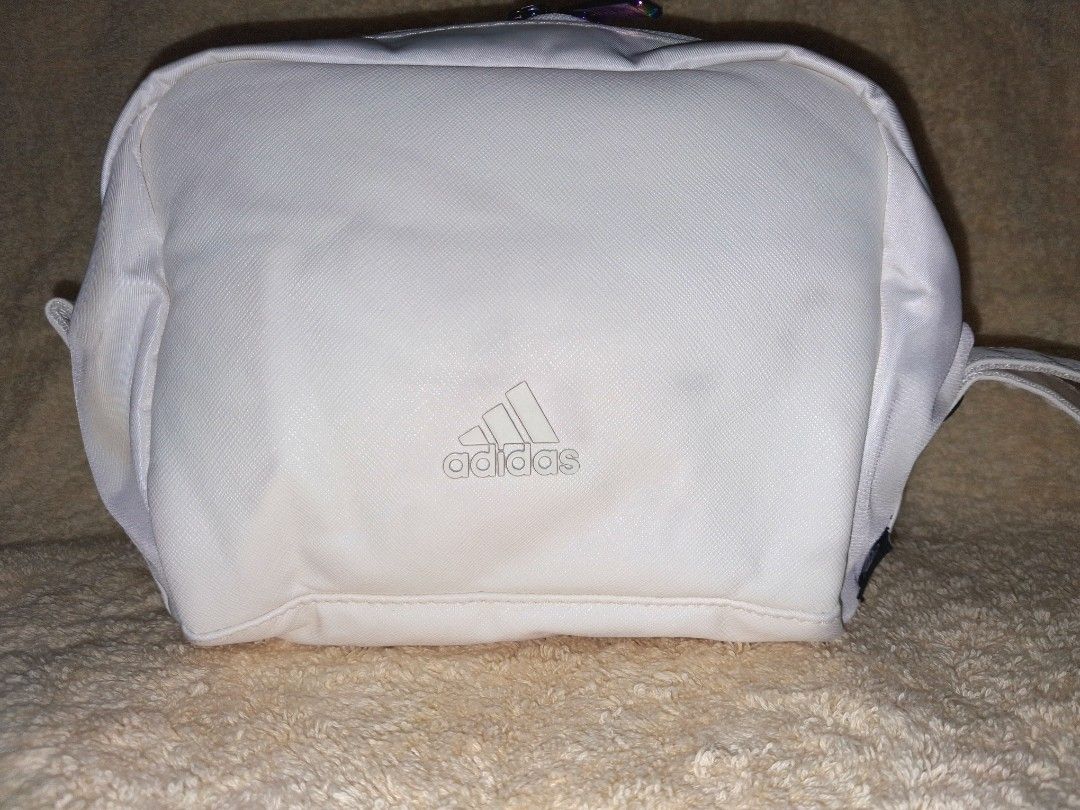 Adidas White Toiletry Bag Pouch With 3 Stripes (Category: Belt bags, Clutches and Pouches) located in Angeles City. Submitted by anneps (Listing ID 1470219127, Image 3). Description: - Brand: Adidas - Color: White with iconic 3 black stripes - Features: Side carry handle and unique rainbow metallic-tinted logo zipper pulls - Interior: Light pink lining with a convenient mesh slip pocket - Dimensions: Approximately 8 inches tall - Perfect for: Tra