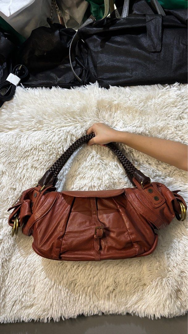 After The Apple Brown Leather Shoulder Bag (Category: Shoulder Bags) located in Rizal. Submitted by kianapreloves (Listing ID 1470210451, Image 2). Description: - Brand: After The Apple - Material: Supple brown leather with visible grain - Handles: Dark brown braided handles - Closure: Secure zipper top closure - Exterior: Front flap pocket with buckle closure and side ring hardware accents - Interior: Roomy storage space.