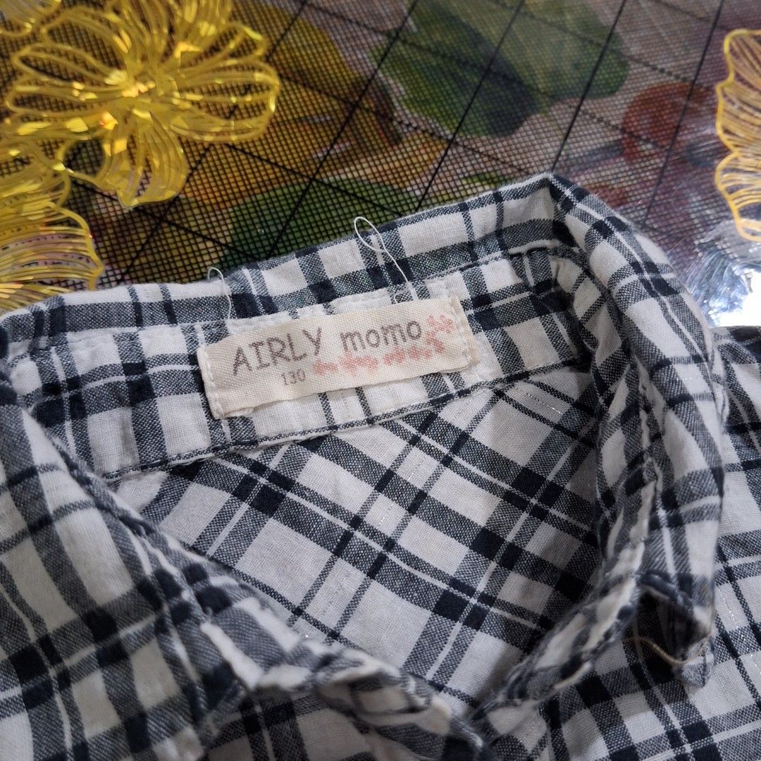 AIRLY momo plaid ruffle bluse/gingham tier (Category: Blouses) located in Pasig City. Submitted by zelzelly (Listing ID 1470289990, Image 3). Description: RFS: Decluterring, fits on me but too small for my arms. • xxs - xs size / 130 on tag 7 to 8yrs old kid size, but it fits on me when I wore this (xs) • AIRLY momo on tag (Japanese brand) Details: • Classic monochrome grid plaid (gingham-style). • Vertical ruffle panels framing the central butto