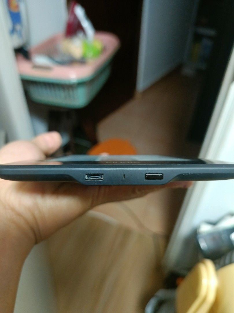 Amazon Kindle E-Reader (Category: E-Readers) located in Singapore. Submitted by livedog_7bdbb1 (Listing ID 1470301970, Image 3). Description: - Model: Amazon e-reader (Black) - Condition: Fully functional screen and battery; visible scratches on the back casing from normal use - Features: Clear display for reading, lightweight design, holds a great charge - Ports: Standard micro-USB charging port next to the power button - Perks: Perfect portable
