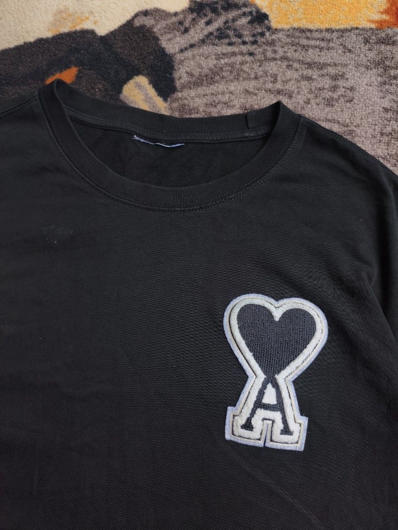 Ami Paris Black T-Shirt with Logo Patch (Category: Tshirts & Polo Shirts ) located in Davao. Submitted by simonandre53791 (Listing ID 1470253506, Image 2). Description: - Brand: Ami Paris - Color: Black with white/grey embroidered heart logo - Material: 100% Cotton, regular fit with classic crew neck - Condition: Pre-loved with visible faded areas and minor light marks near the lower front and chest - Authenticity: 100% genuine, PM for inquiries 