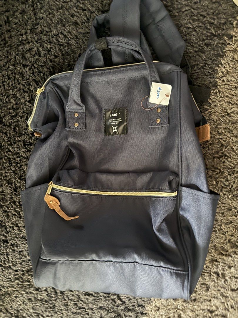 Anello Backpack (Category: Backpacks) located in Makati City. Submitted by triftedandbranded (Listing ID 1470230371, Image 2). Description: - Brand: Anello - Color: Dark blue canvas - Condition: Brand new with thrift store tag attached - Features: Structured-frame main zipper opening, double top handles with snap closure - Pockets: Front zipped pocket with leather-like pull tab and dual side slip pockets - Comfort: Adjustable back shoulder straps