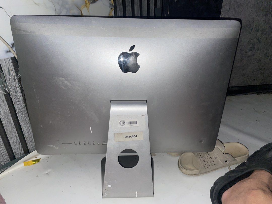Apple iMac A1418 Desktop Computer (Category: Desktops) located in Caloocan City. Submitted by kennanmanalo (Listing ID 1470205731, Image 2). Description: - Model: Apple iMac A1418 - Color/Material: Silver aluminum body - Ports: Multiple USB ports, headphone jack, SD card slot, and Ethernet port - Condition: Powers on successfully; shows heavy dust, smudges, and dirt on the screen, back panel, and stand base (needs cleaning) - Features: Inventory 