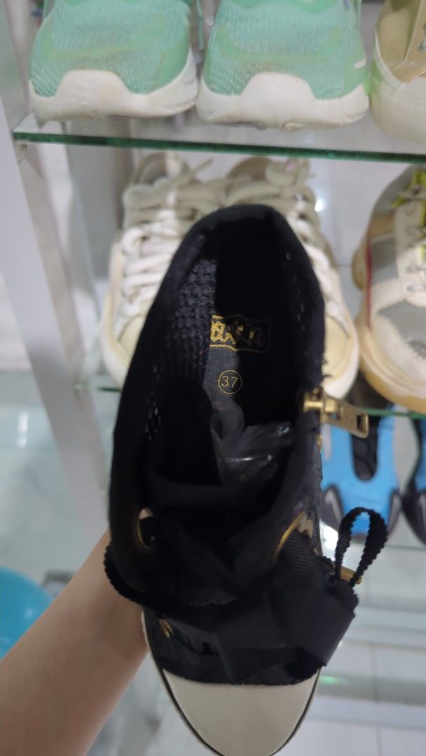 Ash Wedges Lacey Black Sneakers (Category: Sneakers) located in Cavite. Submitted by chocomint.bb (Listing ID 1470309515, Image 3). Description: - Size: 37 (marked clearly on inner sole) - Style: High-top wedge sneakers with extra height - Color/Material: Black patterned fabric upper with rubber toe caps - Details: Chunky ribbon laces and standard lace detailing - Hardware: Chic gold-tone eyelets and convenient side zippers.